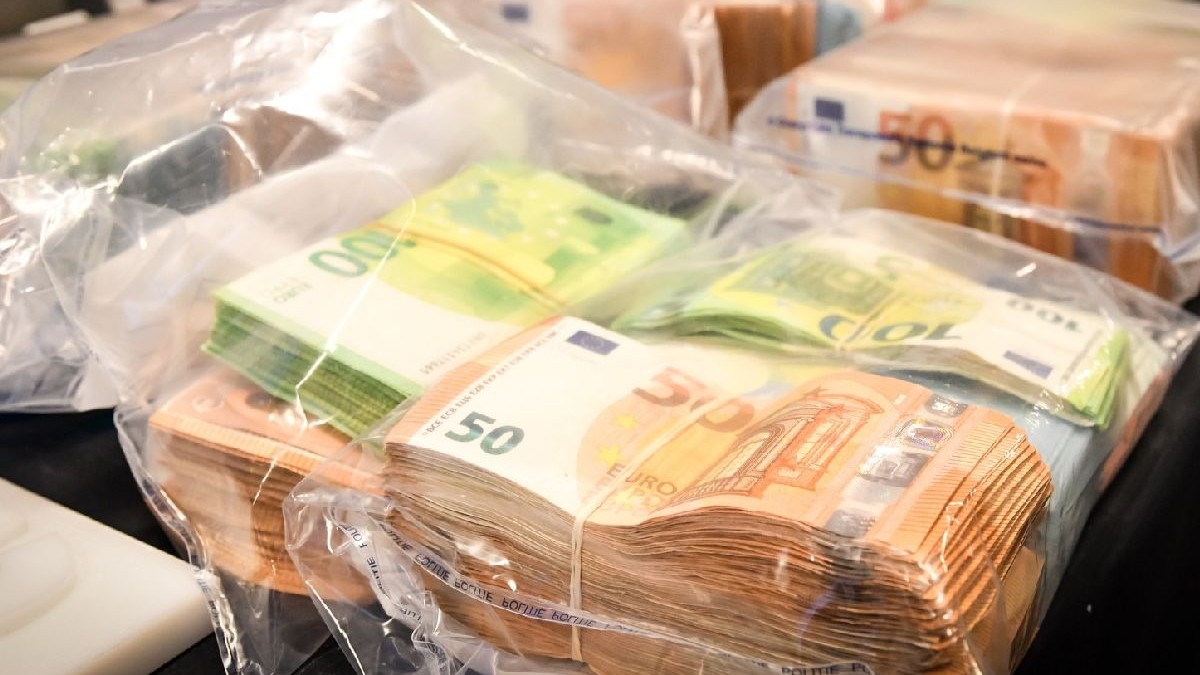 Imaginea prezintă mai multe teancuri de bani, bancnote de 50 și 100 de euro, în pungi din plastic, așezate pe o masă.