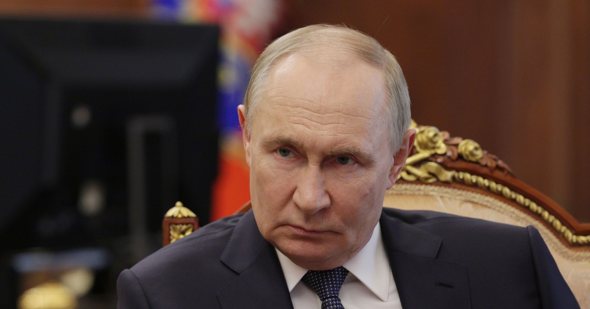 Vladimir Putin surprins în timp ce se încruntă. Liderul de la Kremlin stă pe scaun și poartă un sacou negru, o cămașă albă și o cravată cu buline albe