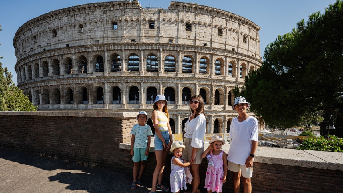 O mamă cu cinci copii pozează având Colosseumul ca fundal, în centrul istoric al orașului Roma, Italia.
