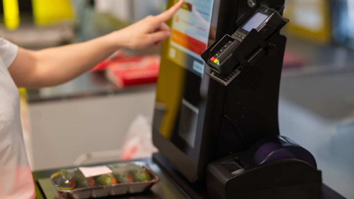 O femeie cântărește castraveți la un serviciu de plată.