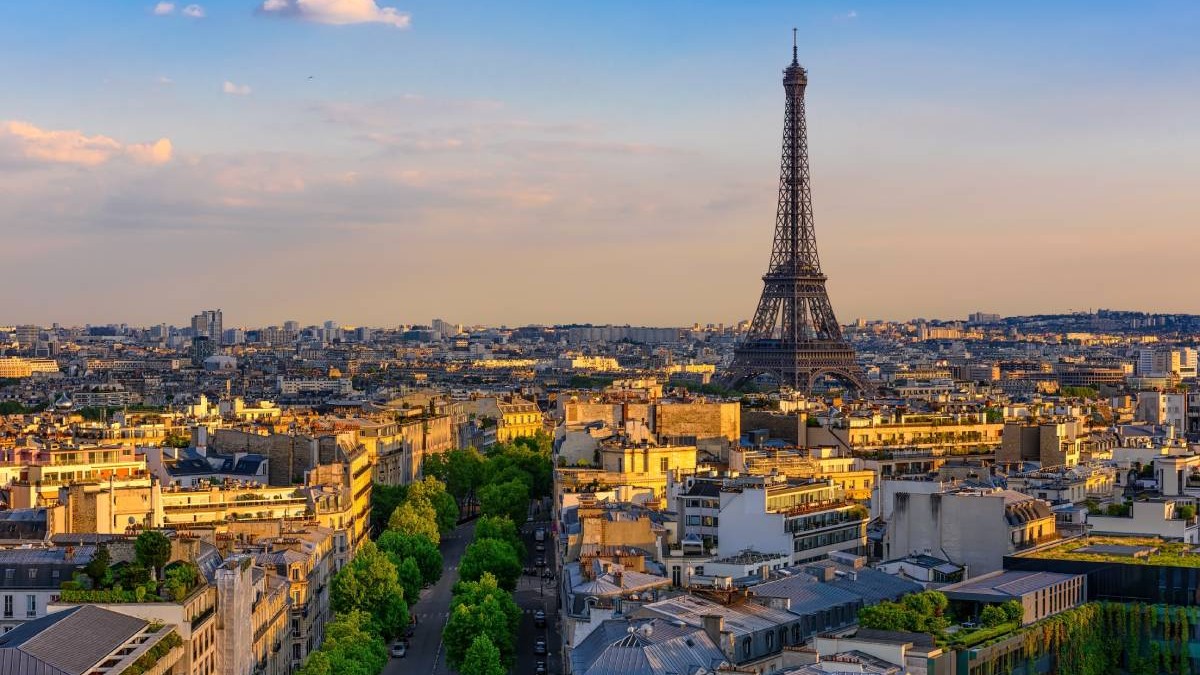 Centrul orașului Paris văzut de sus, la răsărit Lumina soarelui bate peste clădiri, cerul este senin și se vede Turnul Eiffle