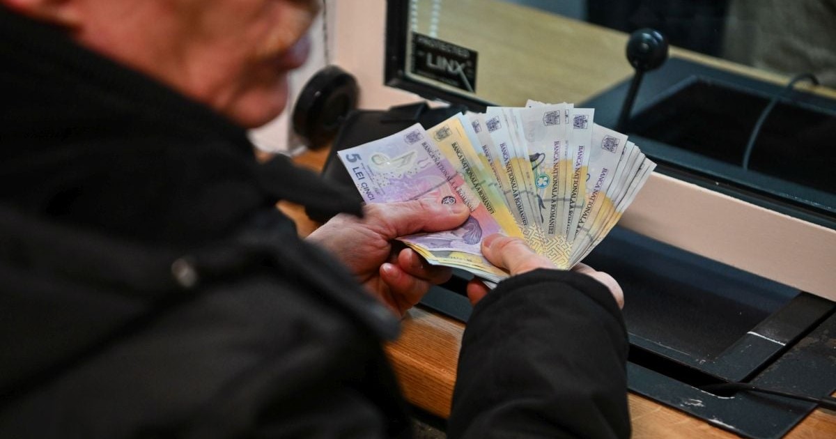 Un bărbat ține în mână mai multe bancnote în fața unui ghișeu, cu care achită taxele la Direcția Fiscală din Brașov, 12 ianuarie 2026