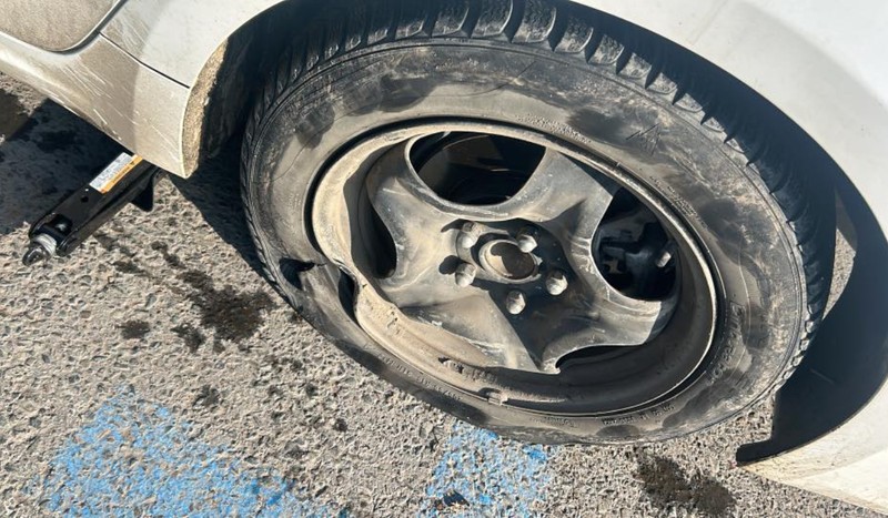 Una dintre mașinile postate de utilizatori: cauciucul este tăiat și janta îndoită după ce șoferul a lovit mașina într-o groapă. Foto: Facebook / InfoTrafic București Ilfov