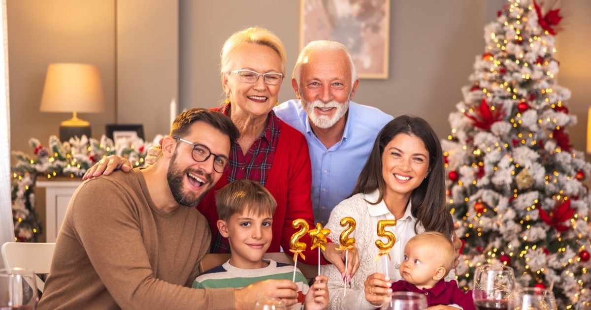 O familie cu doi copii sta la masa de Revelion, iar bunicii stau la poza in spatele lor