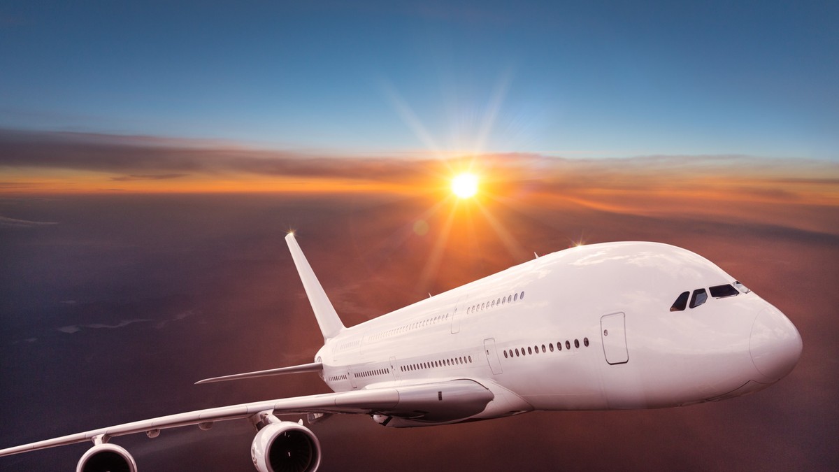 De ce, în general, avioanele sunt vopsite în alb - Imagine cu un avion vopsit în alb, ridicându-se deasupra norilor.