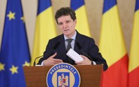 Nicușor Dan, susținând o declarație de presă, având în spate steagurile României și ale Uniunii Europene.