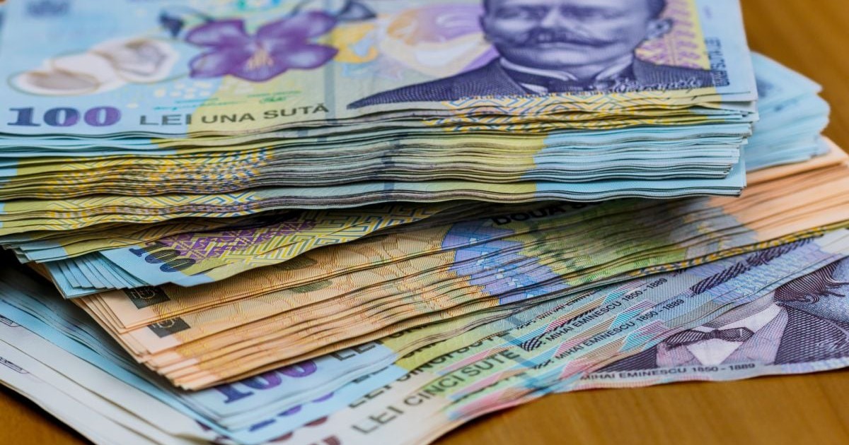 Bani pe o masă de lemn, bancnote de 100 de lei, 200 de lei și 500 de lei, în teancuri, pe o masă de lemn