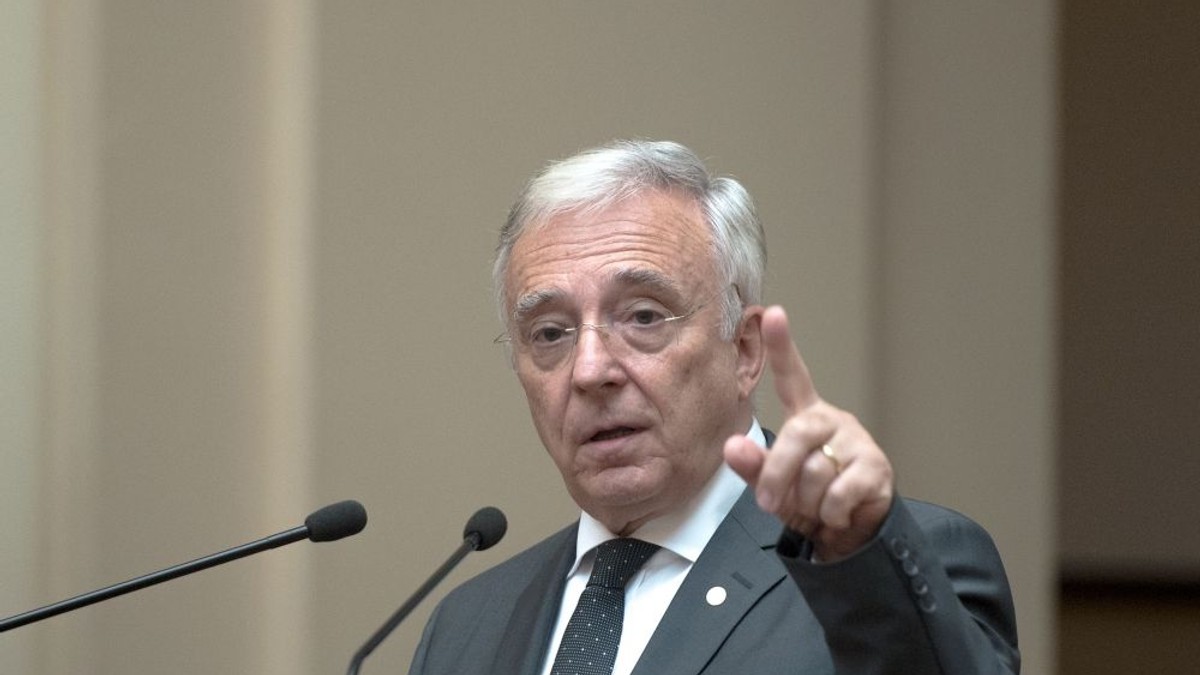 BNR prezintă raportul trimestrial asupra inflaţiei. Mugur Isărescu, la un pupitru, cu mâna stângă ridicată și degetul arătător în aer