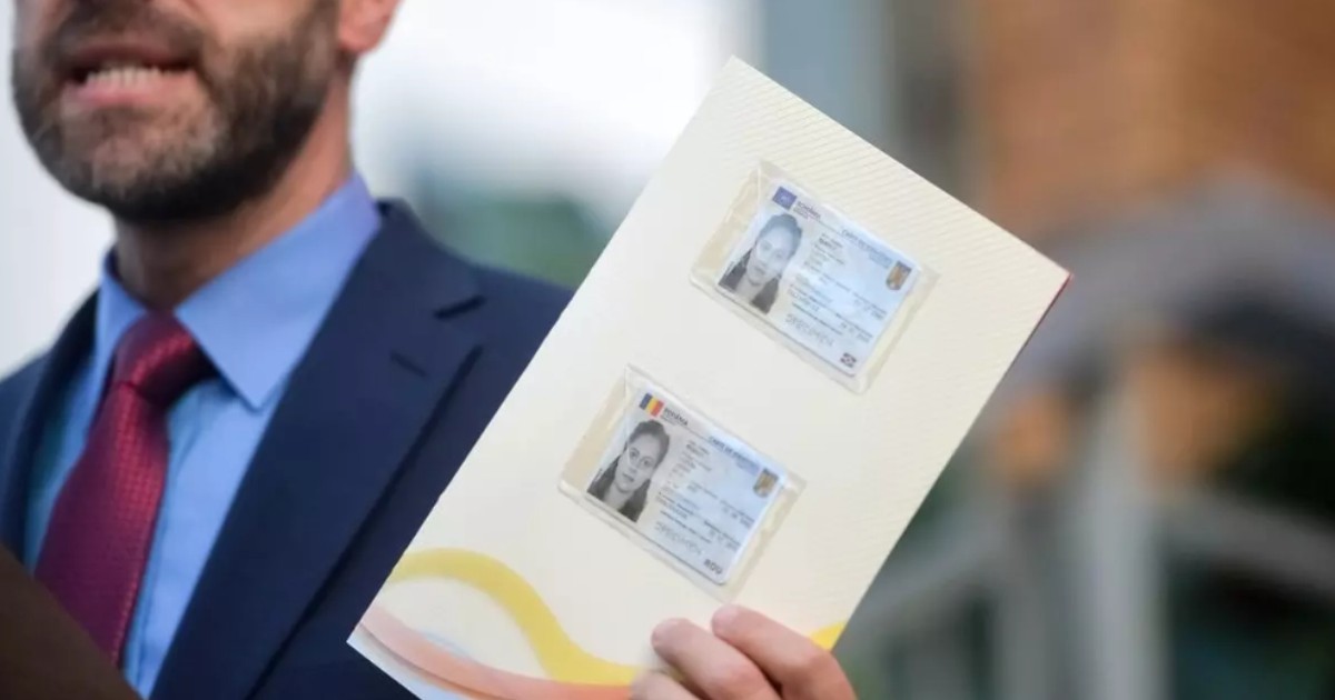 În imagine este ilustrat un bărbat în costum care ține în mână o foaie pe care sunt două cărți de identitate electronice