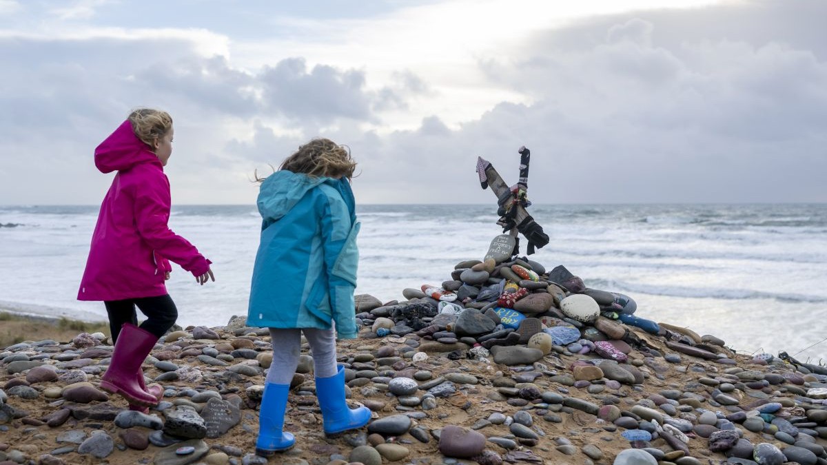 Copii privesc un „mormânt” dedicat lui Dobby – un elf de casă fictiv din romanele și filmele fantastice *Harry Potter* – pe plaja Freshwater West din Castlemartin, Regatul Unit, la 6 noiembrie 2022