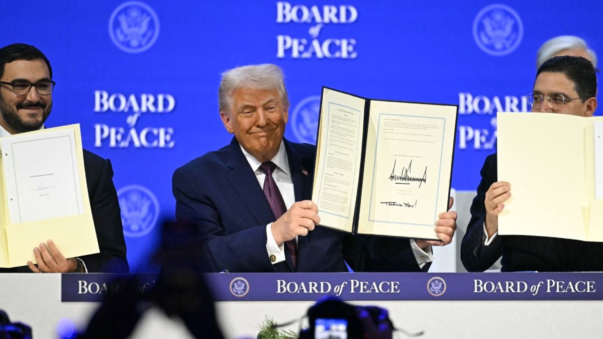 Donald Trump ține în mână Carta Consiliului pentru Pace, la Davos, pe 22 ianuarie 2026, pe fundal albastru cu numele Board of Peace