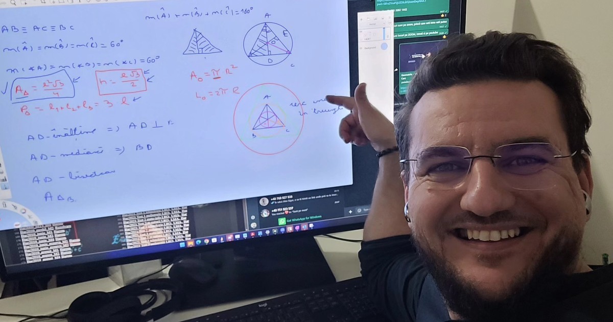 Bărbat care râde și arată cu mâna înspre un monitor de calculator