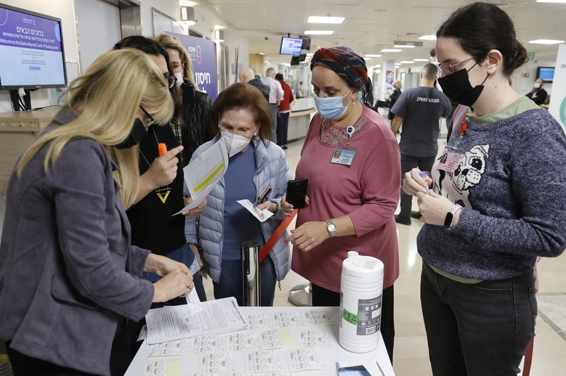 Voluntari din cadrul angajaților Centrului Medical Sheba stau la coadă pentru a primi o a patra doză de vaccin împotriva COVID-19, luni, 27 decembrie 2021 | Sursa foto: Profimedia Images