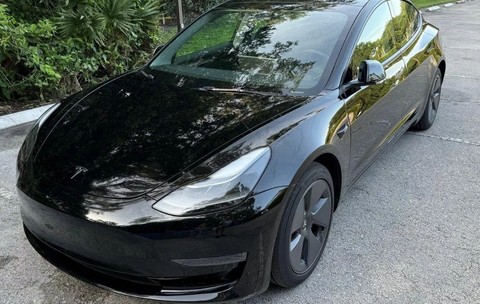 masina neagra marca tesla parcata in fata unei case