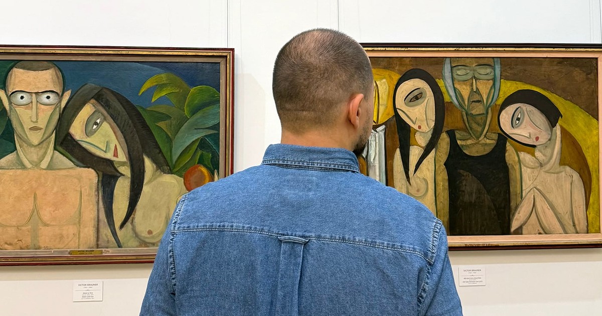 Un tanar se uite la doua tablouri intr-o expozitie