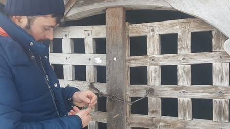 Muzeograful Lucian Robu, în timp ce deschide pivnița casei