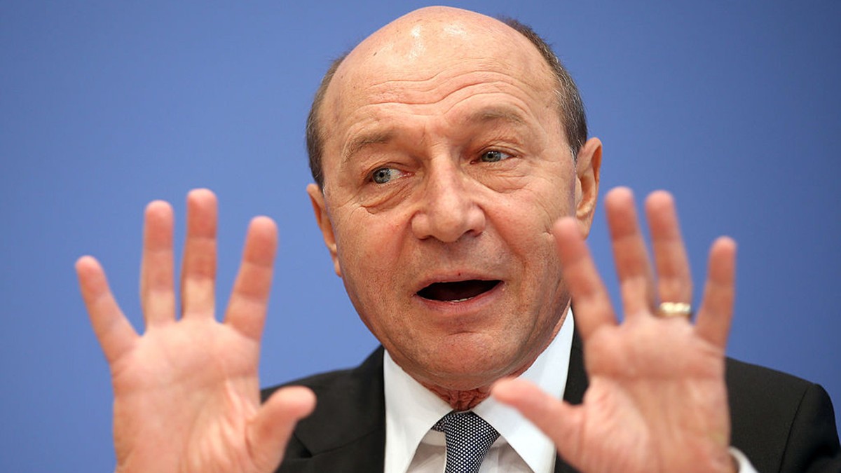 Traian Băsescu cu mâinile lângă față explică ceva.