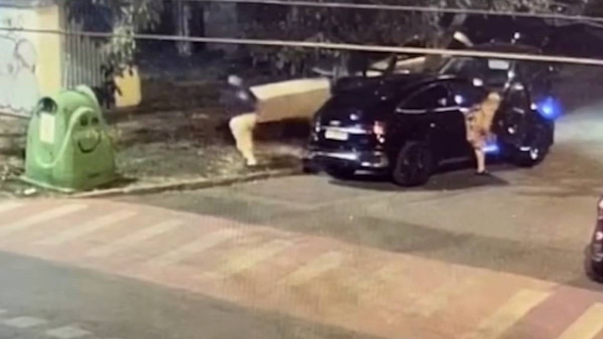 Captură video camere de supraveghere cu un bărbat care este surprins noaptea lângă un Mercedes negru oprit pe o stradă din Timișoara, în timp ce mai multe cutii și obiecte voluminoase sunt lăsate pe trotuar, lângă containerele de gunoi.