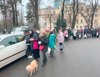 Oamenii nevoiași stau la coadă pentru ajutoare umanitare în curtea bisericii.