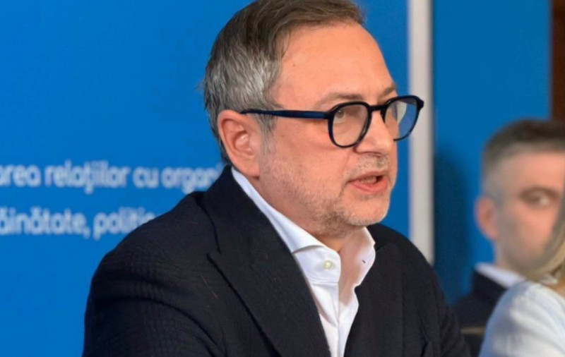 Dan Motreanu în costum negru, la un birou