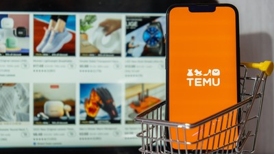 Gdansk, Poland - March 2023 Temu app icon in screen of MacBook Apple computer laptop and mobile Iphone with shopping cart. Temu subsidiary of China based e-commerce platform Pinduoduo. Online shopping