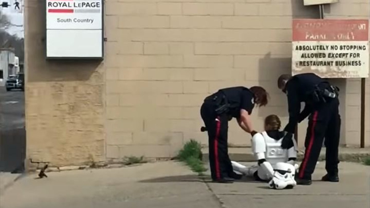 angajată a unui restaurant din Canada a fost încătușată după ce a dansat în costum de Storm Trooper având o armă de jucărie. Fata în costum alb de Storm Trooper încătușată, stând în fund, cu mâinile la spate, și doi polițiști stând aplecați lângă ea