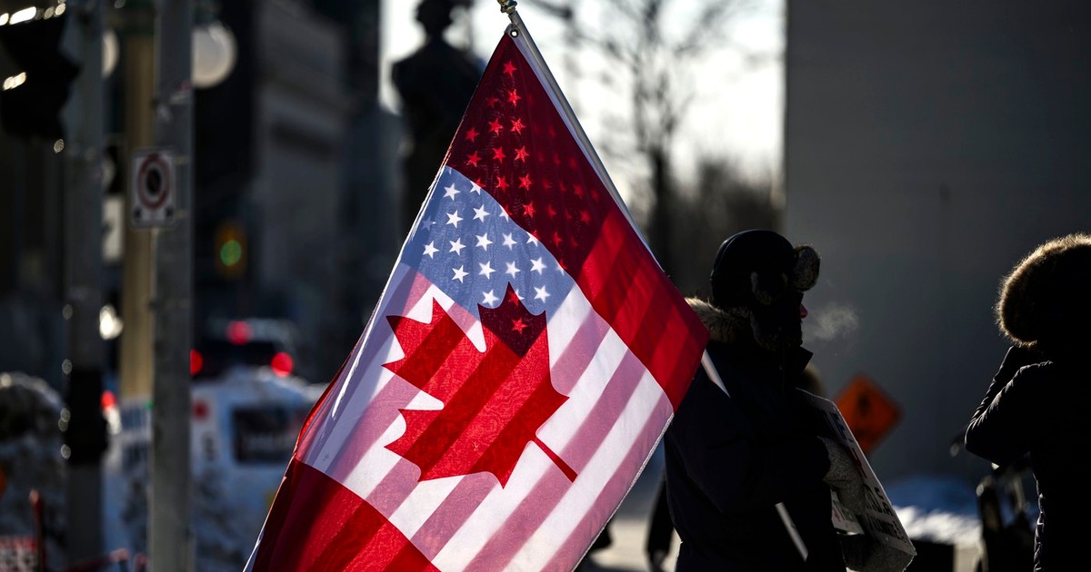 Un protestatar canadian, cu steagurile suprapuse ale SUA și Canadei, în fața Parlamentului de la Ottawa, pe 1 februarie 2025 Foto: Profimedia