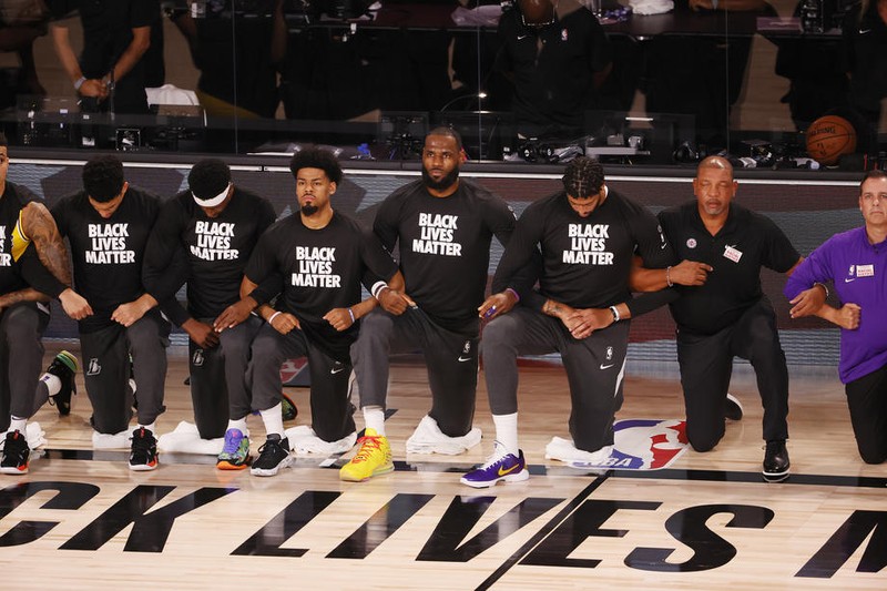 Jucătorii de la Los Angeles Lakers și de la Clippers au stat în genunchi și s-au ținut de braț în timpul imnului național înainte de jocul lor la complexul ESPN Wide World of Sports, care a repornit sezonul NBA FOTO: EPA