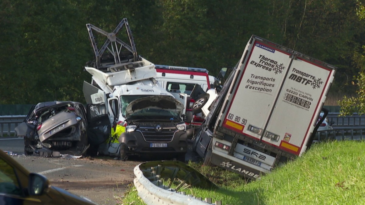 Locul unui accident rutier grav pe o autostradă, implicând un camion frigorific înclinat în șanț și mai multe vehicule utilitare și autoturisme puternic avariate.