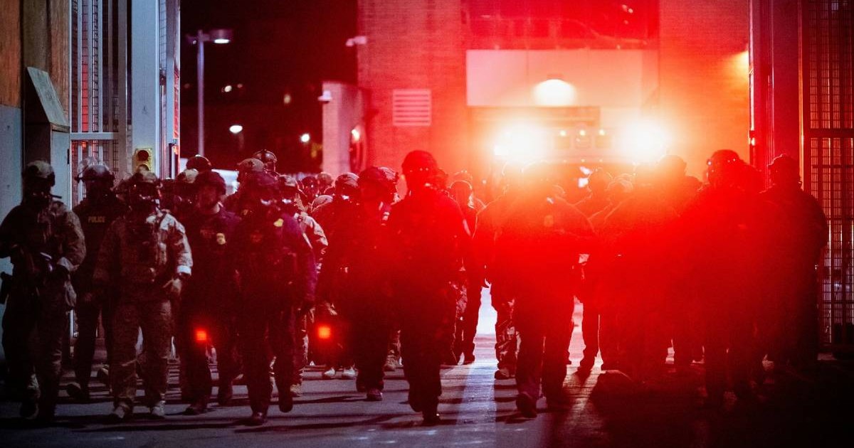 Ofițeri de securitate noaptea, pe strada, se vad lumini rosii, actiuni desfășurați în apropierea unui centru al Serviciului de Imigrări și Control Vamal al SUA din Portland, Oregon, duminică, 5 octombrie 2025.