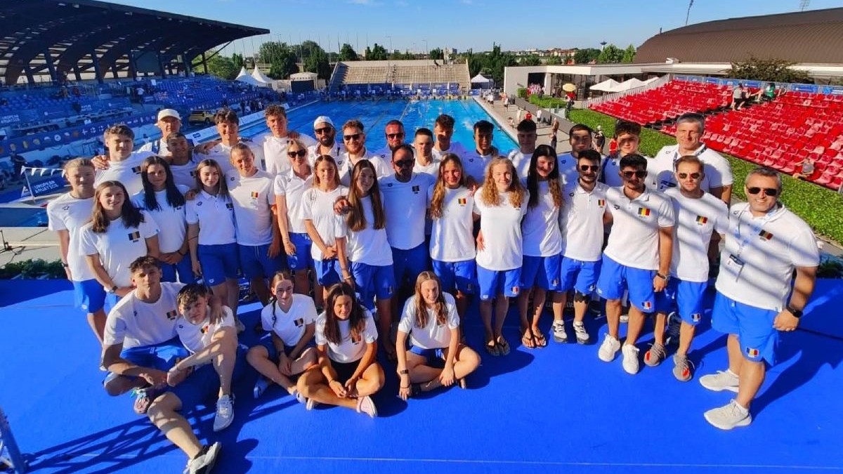 În imagine e echipa de înot a României, juniori, asezați pentru o poză de grup la finalul CAMPIONATELE EUROPENE DE INOT pentru juniori, imbrăcați in tricouri albe si șort albastru, in spatele lor un bazin de inot, - Samorin 1-6.07.2025,