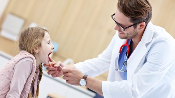 Medic  examinand un copil pentru suspiciune de streptococ beta hemolitic 