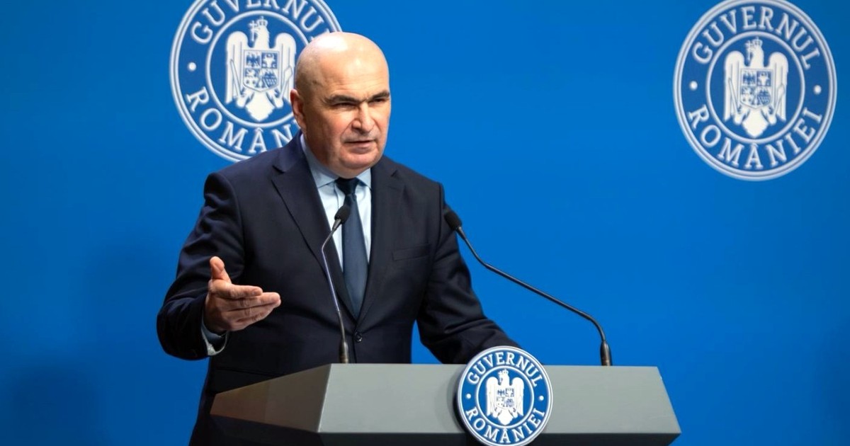 Ilie Bolojan, premierul României, îmbrăcat în costum, la birou, cu un laptop în față, la ședința de Guvern