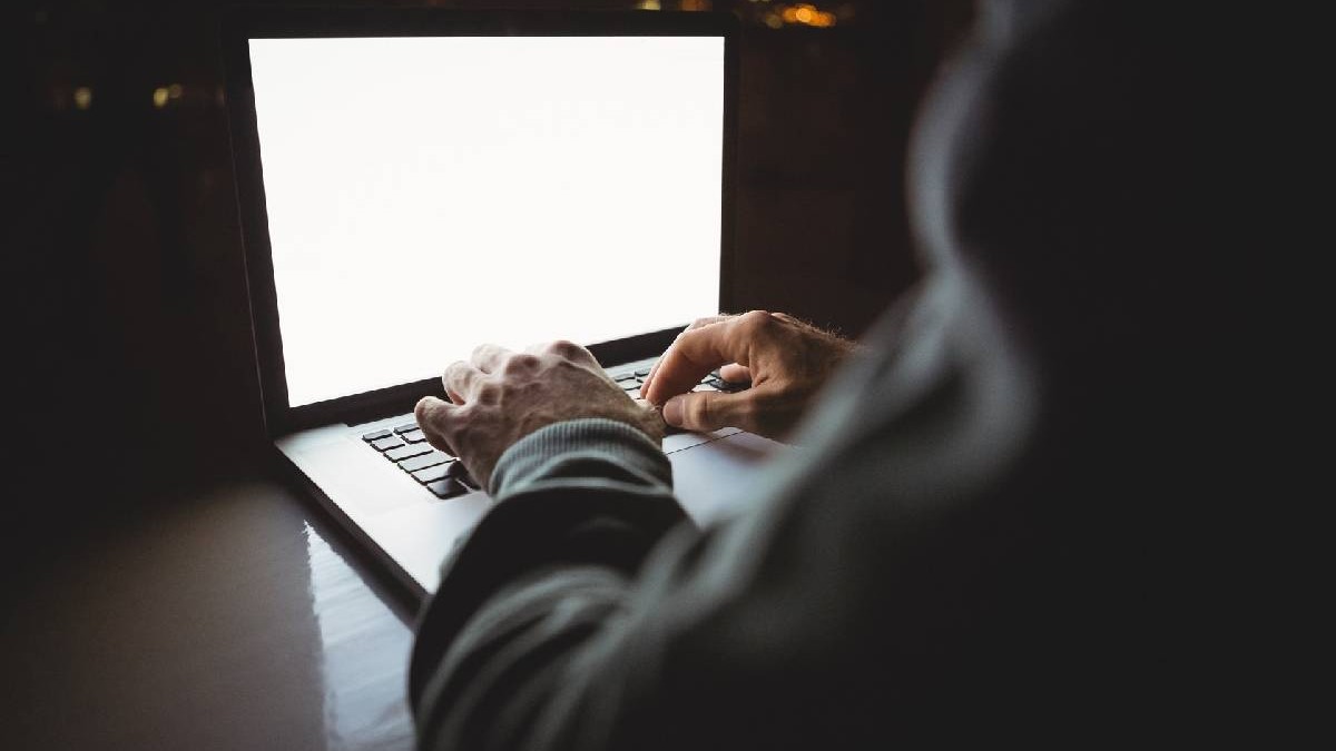 un laptop e deschis și se observă mâinile cuiva care-l manipulează