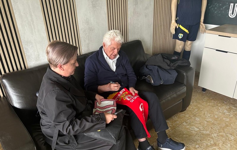Mircea Dridea semnează pe un fular cu însemnele lui FC Liverpool