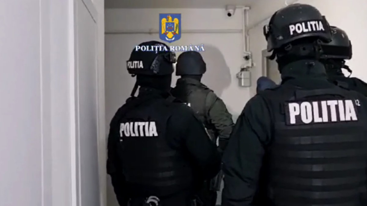 Mai mulți polițiști la ușa unui apartament în vederea unei percheziții