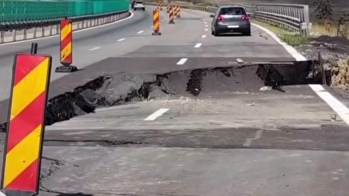 O porțiune de asfalt surpată pe o autostradă, unde zona afectată este semnalizată cu balize rutiere temporare de avertizare.