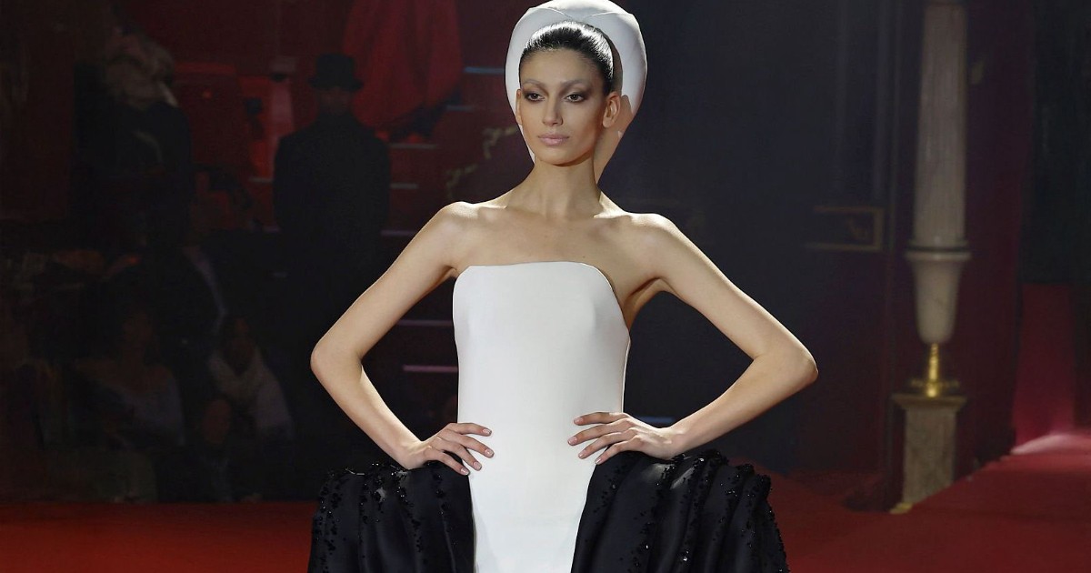 Irina Motoc îmbrăcată în rochie albă cu negru, în timpul unei defilări de modă.