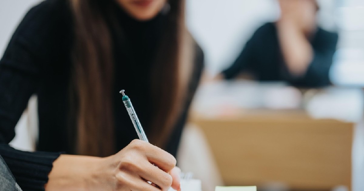 O elevă ia notițe în timpul orei, în sala de clasă