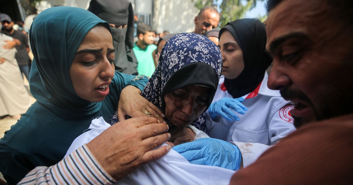 Palestinienii jelesc trupurile învăluite în învăluire ale rudelor, ucise într-un atac israelian, înainte de procesiunea funerară de la spitalul Al-Shifa din orașul Gaza, pe 15 iulie 2025