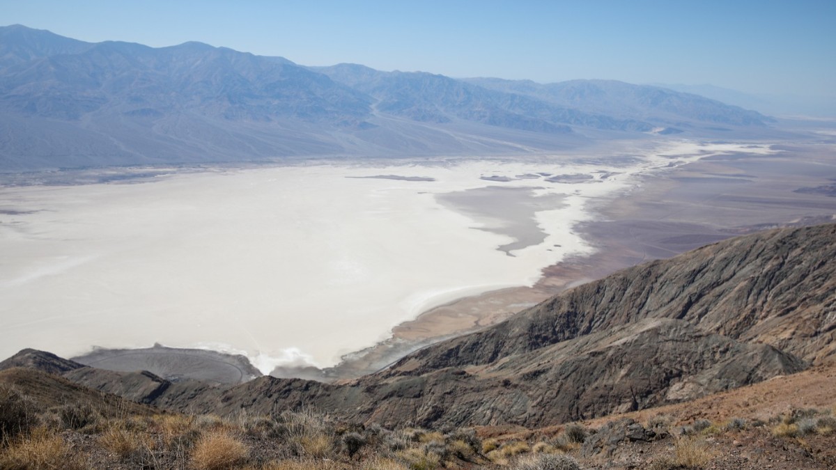 Imagine văzută de sus cu Bazinul Badwater din Parcul Național Valea Morții, California, SUA, înconjurat de lanțuri muntoase.