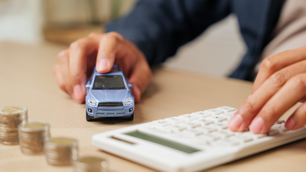O persoană are o mașină de jucărie într-o mână, iar cu cealaltă mână calculează taxele