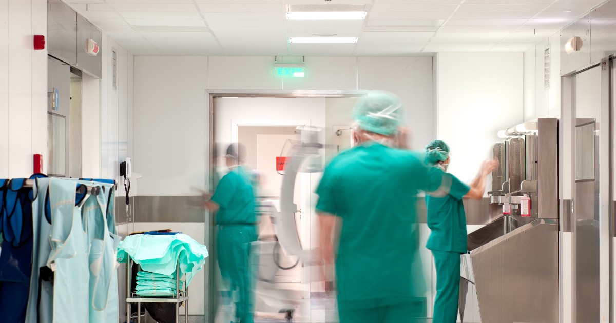 Un coridor de spital unde personalul medical îmbrăcat în costume chirurgicale verzi este surprins în mișcare