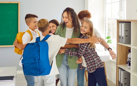 Elevi fericiți, alături de învățătoarea lor. Poză cu caracter ilustrativ. Foto: Shutterstock