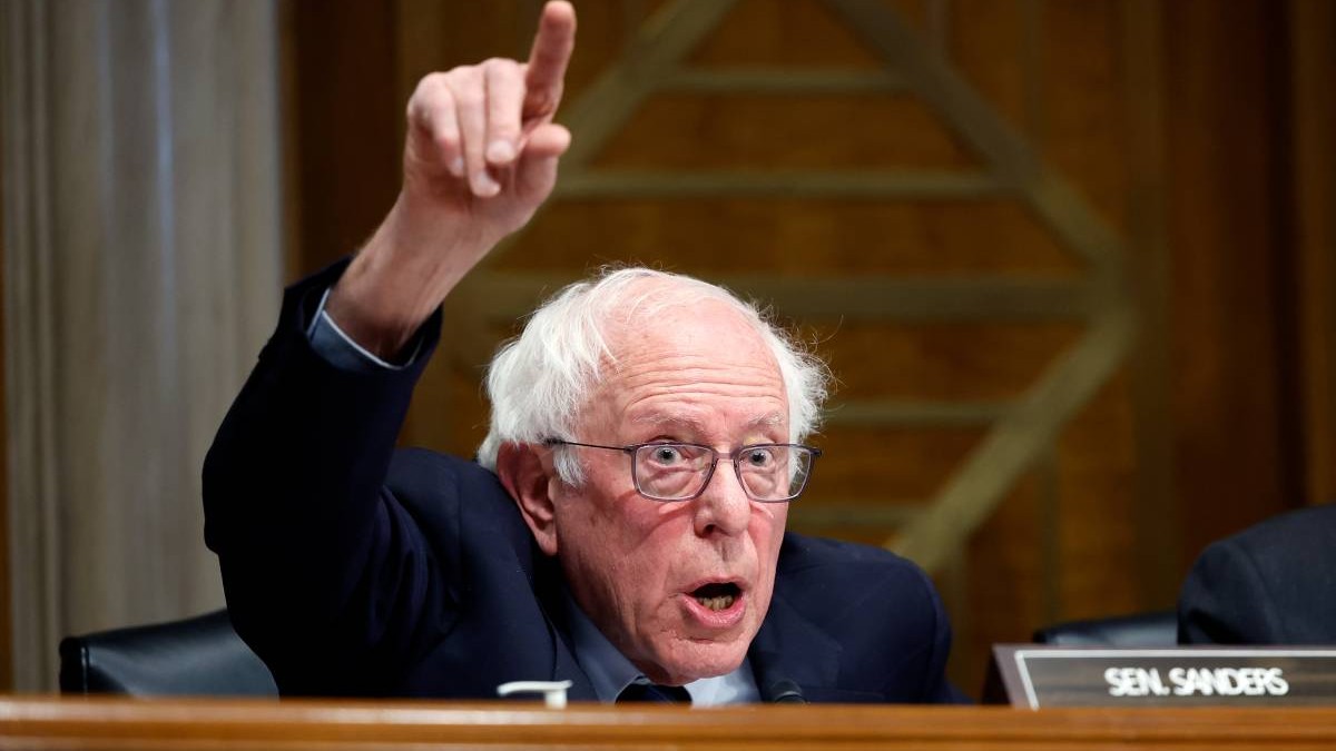 Bernie Sanders, în cadrul unei ședințe, ridicând spre cer degetul arătător al mâinii drepte.