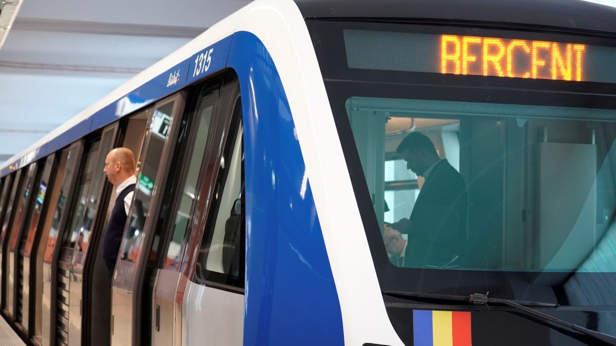 tren metrou albastru cu alb oprit in statie cu usile deschide