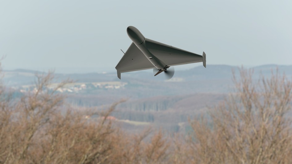 O dronă militară gri în formă de aripă triunghiulară zboară la joasă altitudine deasupra unei zone împădurite și a unui peisaj deluros. Poză cu caracter ilustrativ. Foto: Shutterstock