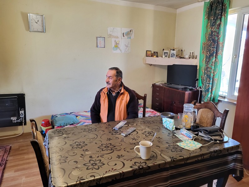 În sufrageria locuinței din Tserovani, cu desenele nepoților pe perete și portretele copiilor pe un colț de etajeră.