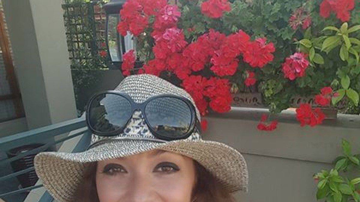 Anca Țurcașiu, în tricou alb și cu pălărie, își face un selfie în grădină