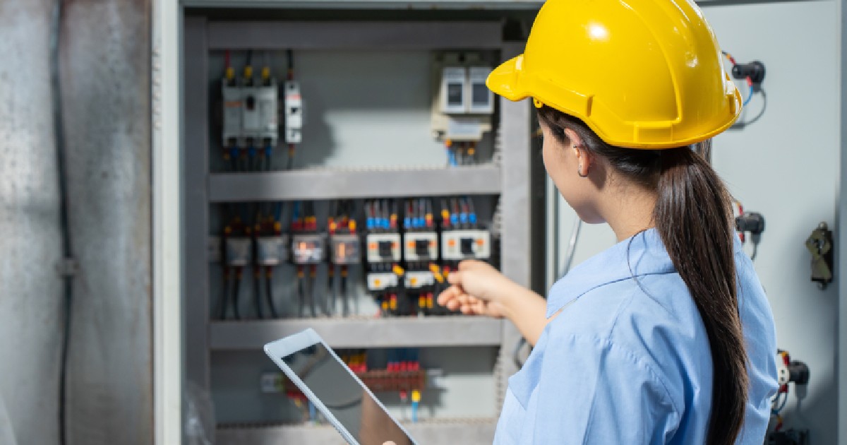 Femeie inginer electrician care lucrează la verificarea serviciului de întreținere a circuitului principal de siguranțe electrice și a sistemului de alimentare cu energie electrică într-o fabrică industrială